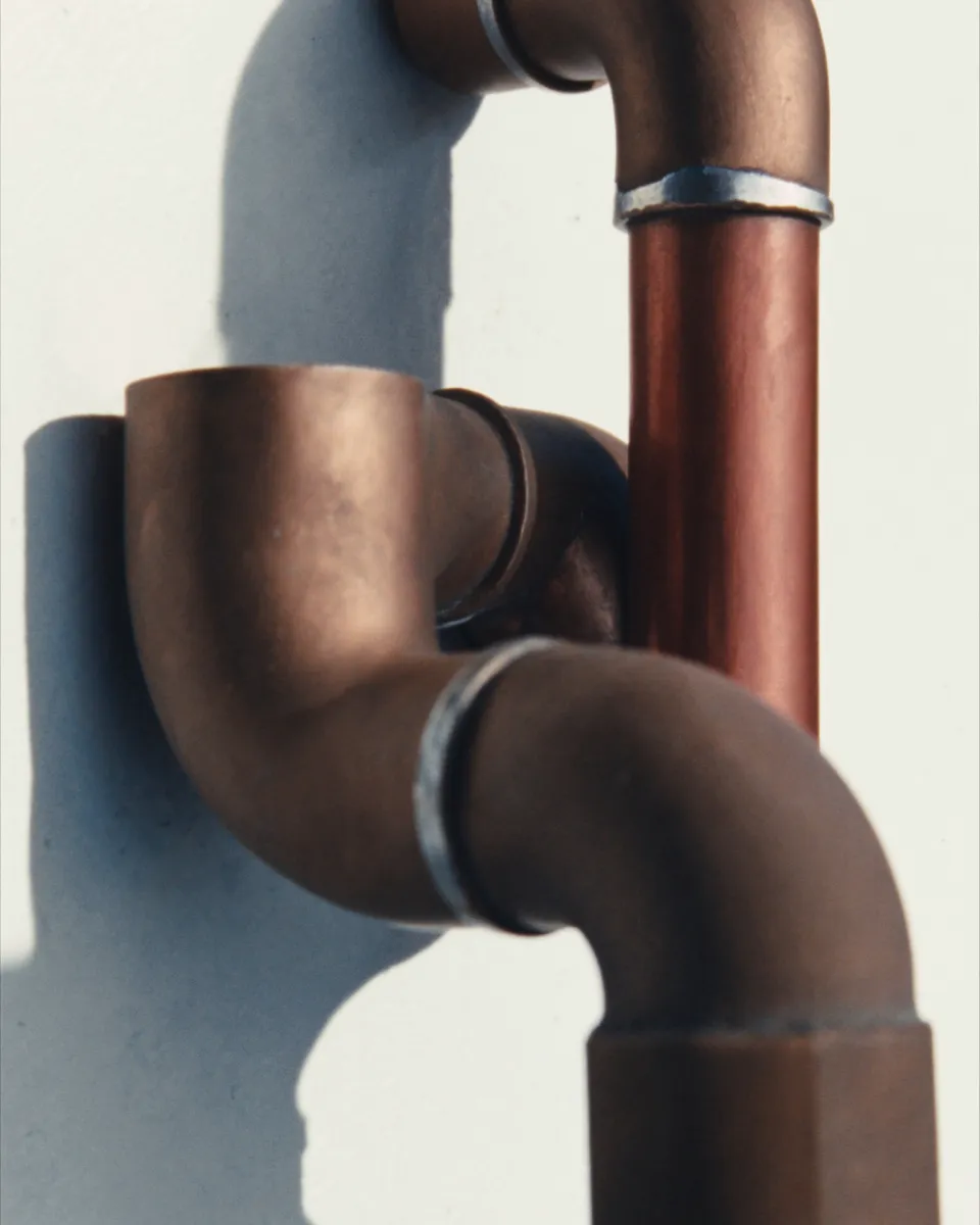 Close-up of soldered copper pipe joints in cold morning light.