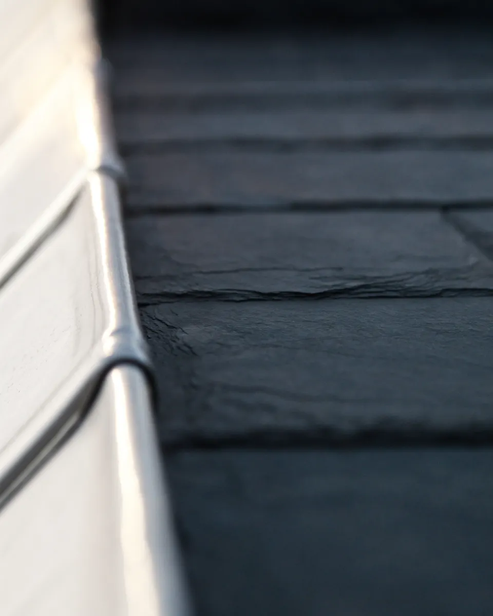 Natural slate tiles overlapping a folded zinc flashing.