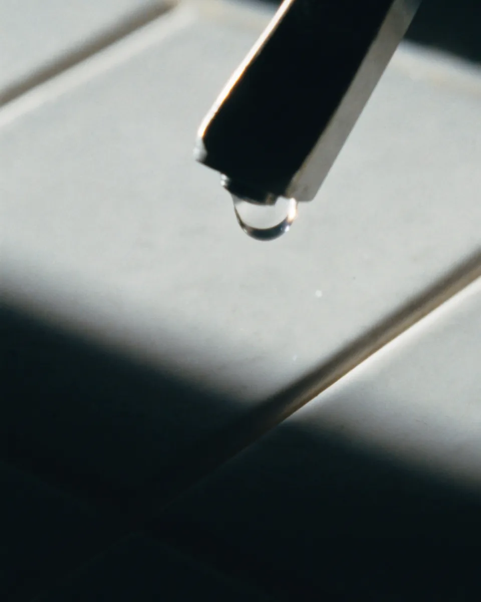 Matte ceramic tile and a brushed steel tap spout.